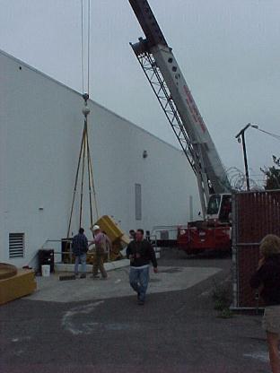 Caterpillar 3512 diesel engine generator skid being rigged down a basement stairway opening.